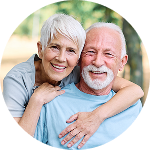 Smiling senior couple embracing and laughing together outdoors.